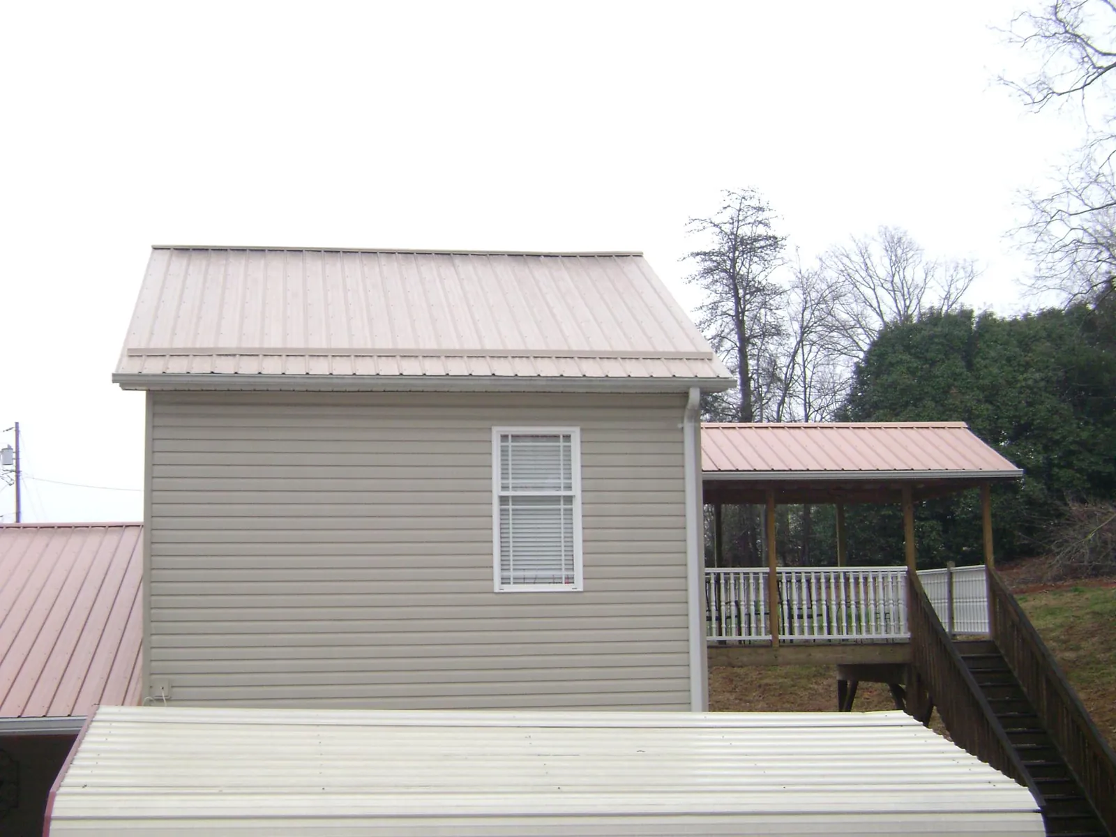 Tan metal roofs on a two story addition and attached porch, from a Roof Replacement job in Rocky Hill
